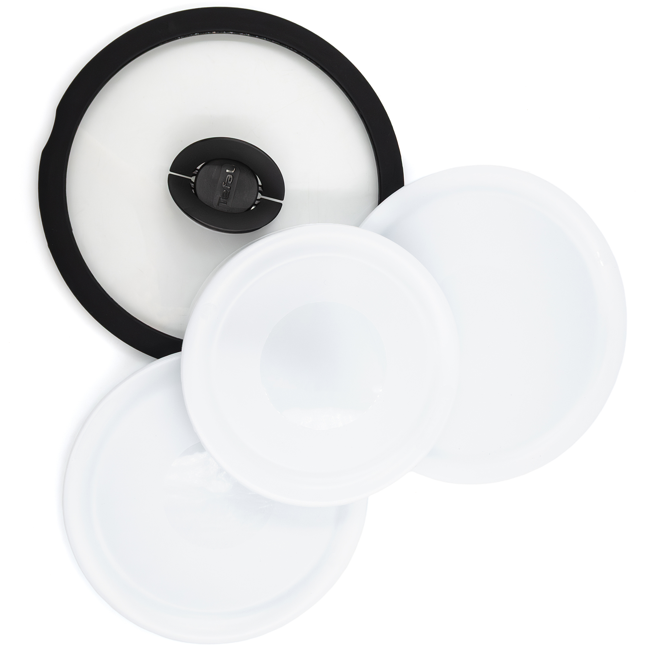 Cztery pokrywki z zestawu Tefal Ingenio Emotion: jedna szklana z czarną obręczą i trzy białe, plastikowe